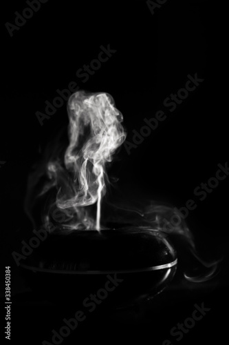 Abstract figures of white flowing steam from a diffuser on a black background.