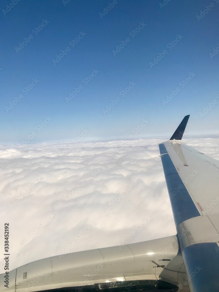 Beautiful heavens gate high above the clouds: Idyllic aerial view from a airplane window with a lovely light blue sky & fluffy white clouds in the atmosphere gives a feeling of freedom