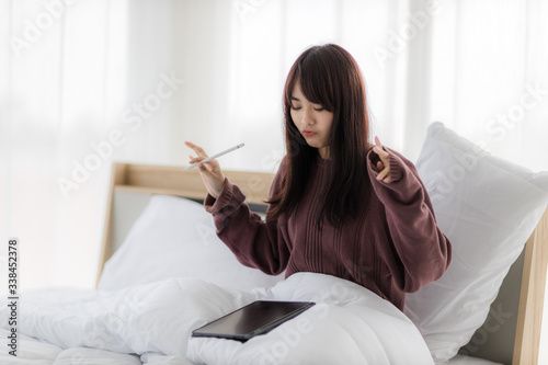 Asian woman using tablet for working, educational, e-commerce, social media in her bed. corovavirus covid-19, stay at home, work form home concept. photo