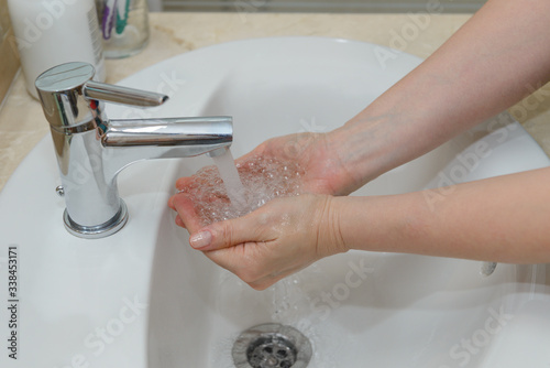 female hands in soapy foam under tap water close-up