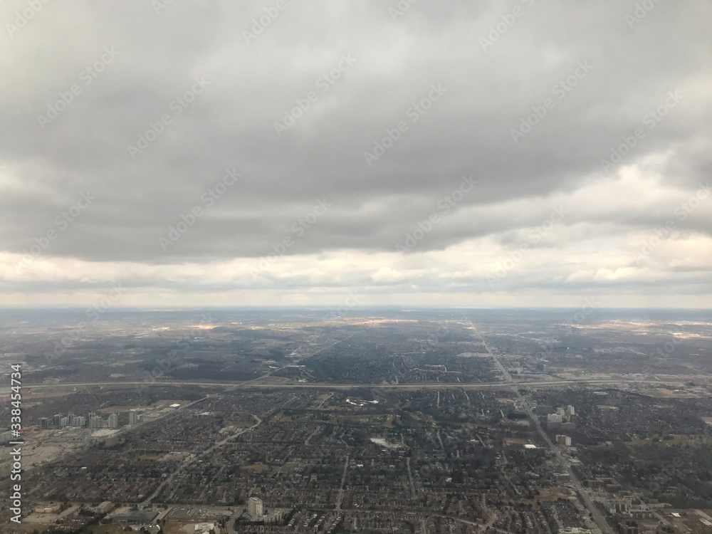Obraz premium Elevated / aerial view of a residential neighborhood suburbs of Toronto (Ontario, Canada, North America) with townhouses, skyscrapers, transportation system, roads & trees from above