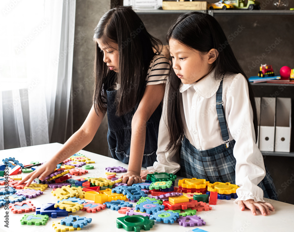 Fototapeta premium Two little girl are playing plasticine together,with interested feeling,at home studio,Lens flare effect,blurry light around