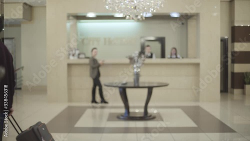 Side view of young Caucasian woman and man passing hotel vestibule in different directions. Male and female guests arriving and leaving luxurious accommodations. Lifestyle, travelling, tourism, luxury