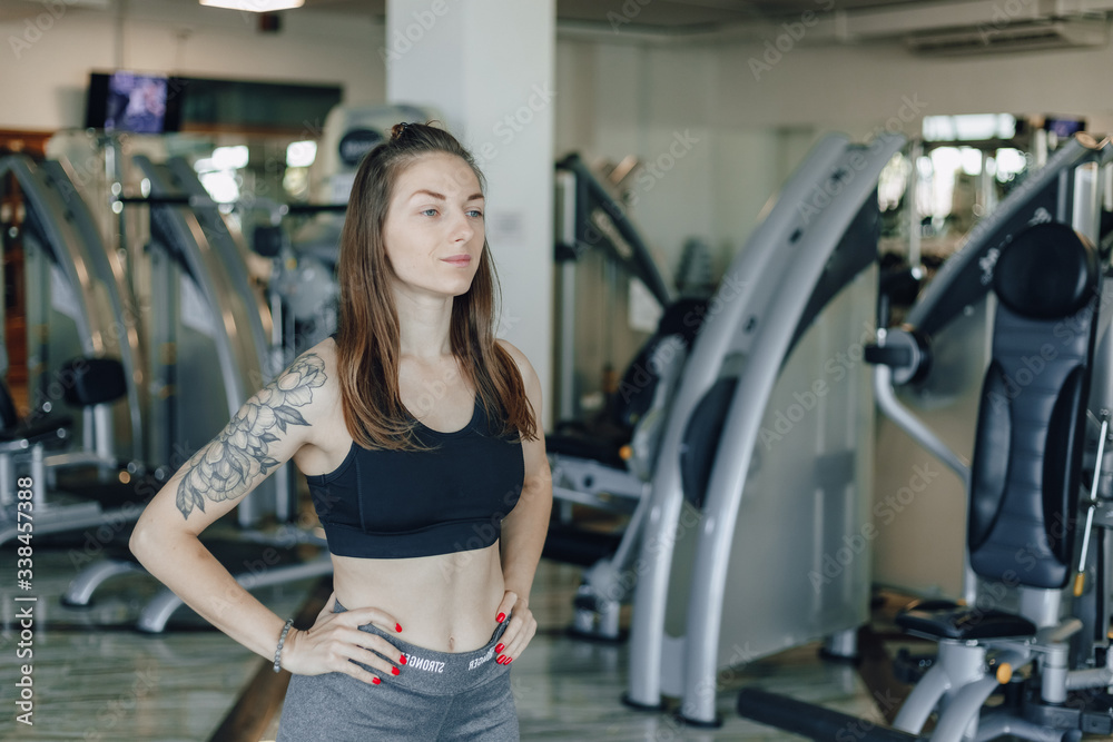 Attractive athletic girl stands on the background of simulators in the gym. healthy lifestyle. Attractive athletic girl stands on the background of simulators in the gym. healthy lifestyle.