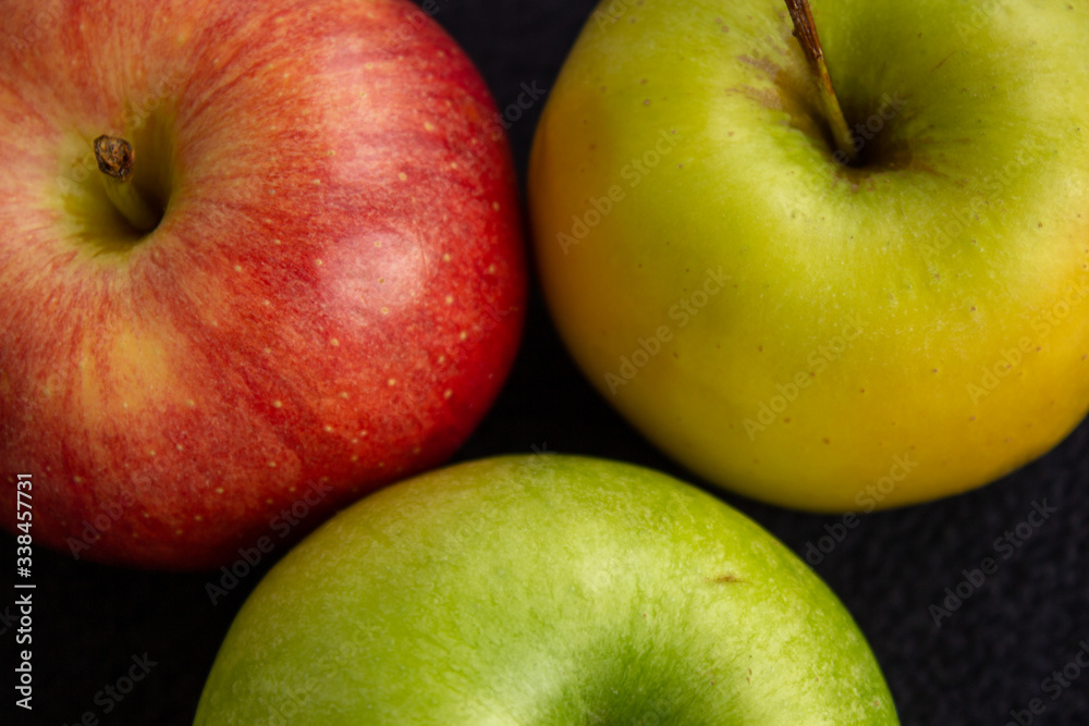 Three apples, one green and two red and yellow on a dark background Three apples, one green and two red and yellow on a dark background