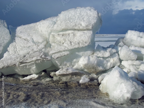 Ice drift on the Dnieper river. Big pieces of white ice against blue sky. Large ice floes floating on the Kremenchuk water reservoir, Dnipro river. Svetlovodsk, Ukraine. Blocks of broken ice cracking photo