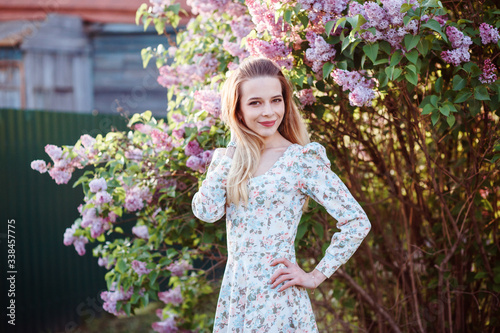 Beautiful european woman is spending time outdoors in the countryside. Lilac bush in the background. Portrait of the charming lady, spring time. 