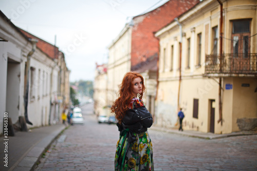 beautiful red-haired girl walks along the old streets of Vyborg
