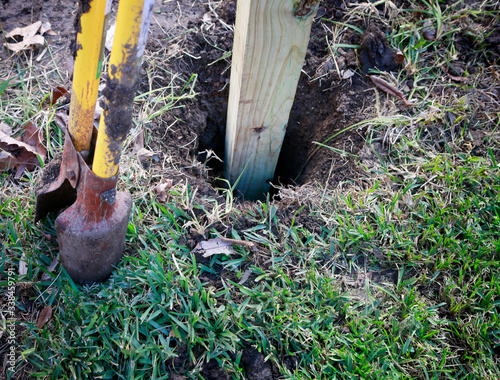 Building new privacy fence in progress: wooden post in hole ready for concrete foundation