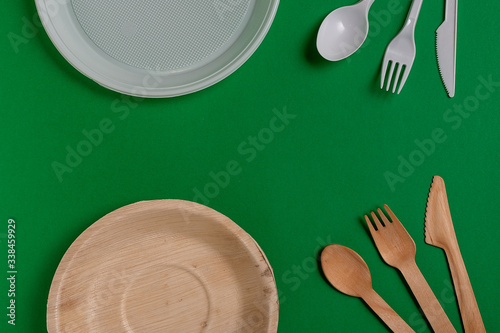 From above plastic utensils versus ecological lumber forks and knives against freen background