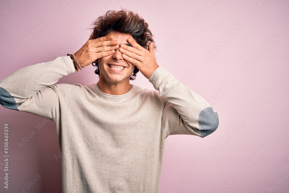 Young handsome man wearing casual t-shirt standing over isolated pink background covering eyes with hands smiling cheerful and funny. Blind concept. Young handsome man wearing casual t-shirt standing over isolated pink background covering eyes with hands smiling cheerful and funny. Blind concept.