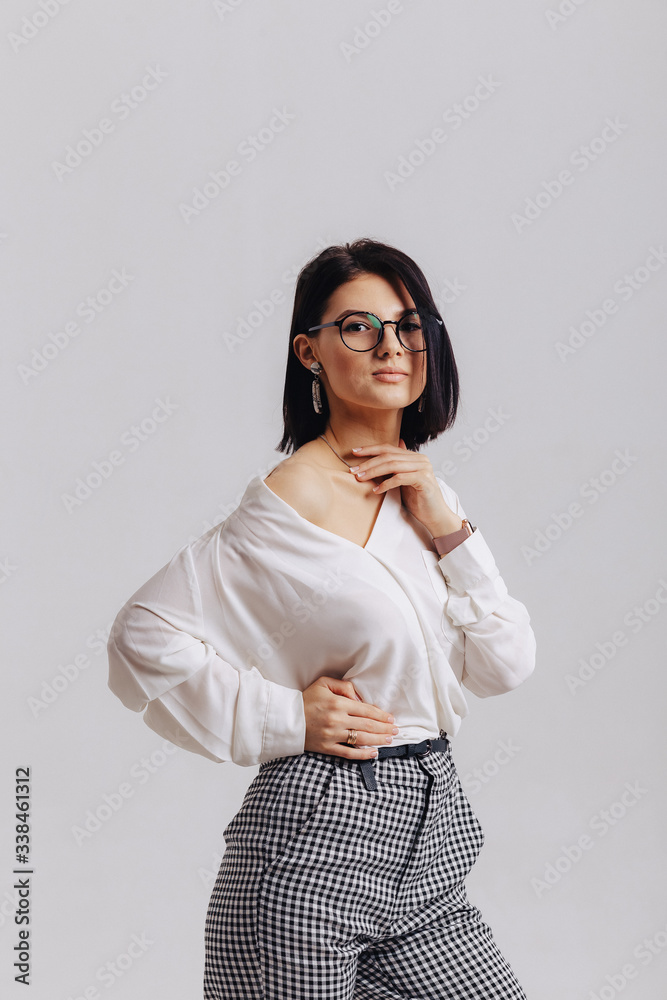 attractive stylish young girl in business clothes posing on light background in studio. concept of stylish clothes and sophistication. attractive stylish young girl in business clothes posing on light background in studio. concept of stylish clothes and sophistication.