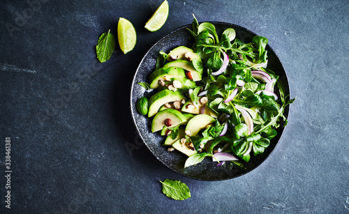 Green leaf vegetable salad with avocado, fresh herbs and hazelnuts. Flat lay. Copy space