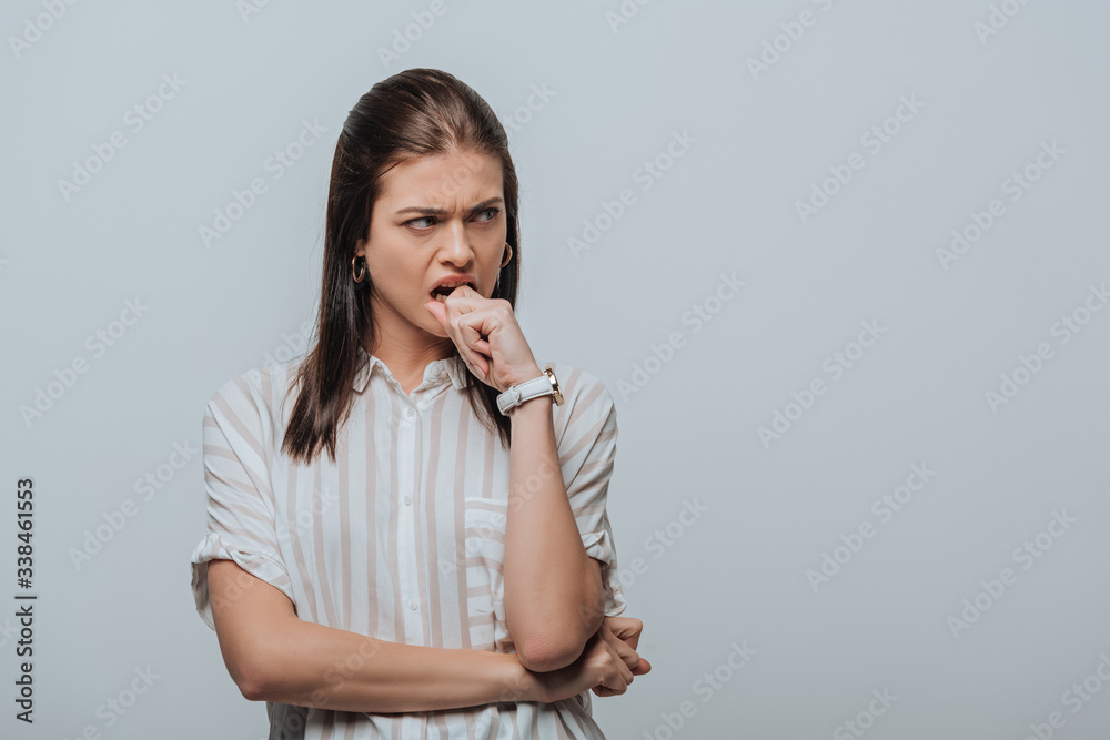 Angry woman with hand near mouth looking away isolated on grey Angry woman with hand near mouth looking away isolated on grey