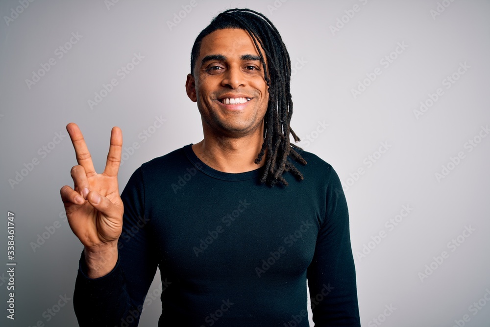 Young handsome african american man with dreadlocks wearing black casual sweater smiling with happy face winking at the camera doing victory sign. Number two.
