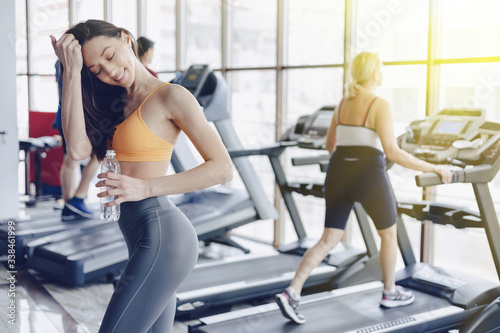 young attractive girl in the gym drinking water on the background of treadmills