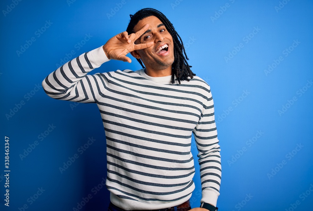 Young handsome african american afro man with dreadlocks wearing casual striped sweater Doing peace symbol with fingers over face, smiling cheerful showing victory Young handsome african american afro man with dreadlocks wearing casual striped sweater Doing peace symbol with fingers over face, smiling cheerful showing victory