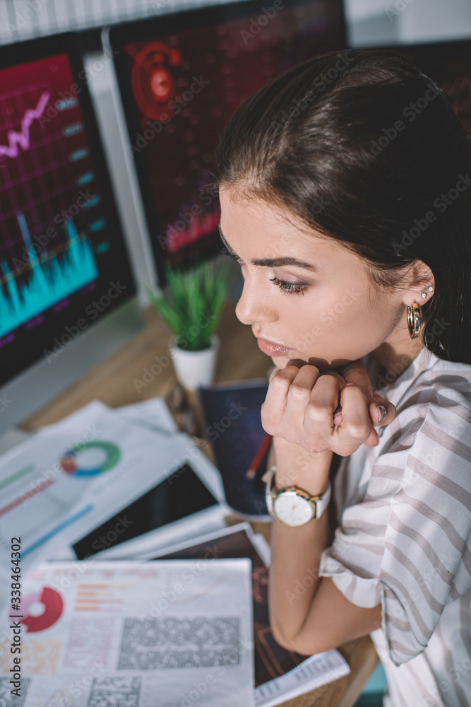 Selective focus of information security analyst sitting at table with papers and computers