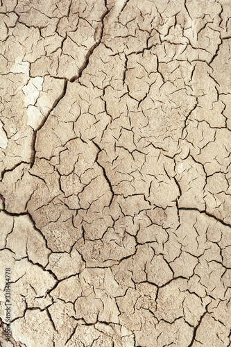 Cracks in the earth in rural areas. Ground texture background. Dry soil abstract vertical photo. Mosaic pattern