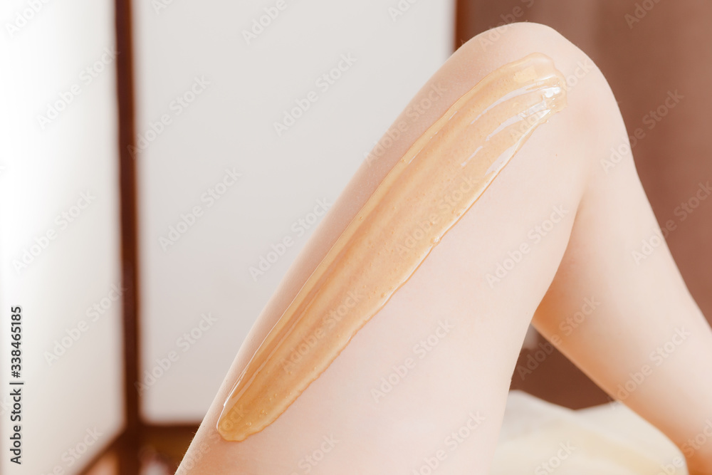 Close-up Of A Beautician shugaring depilation Woman's Leg In Beauty Spa. Body hair removal. Hair removal process on female leg with epilation Close-up Of A Beautician shugaring depilation Woman's Leg In Beauty Spa. Body hair removal. Hair removal process on female leg with epilation