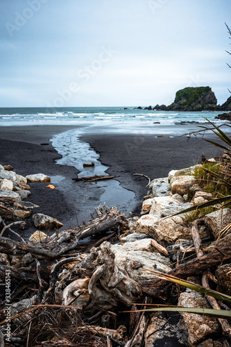 Beautiful image of a beach at low tide with wet rocks in the foreground taken on a cloudy winter day in Cape Fouldwind, New Zealand photo