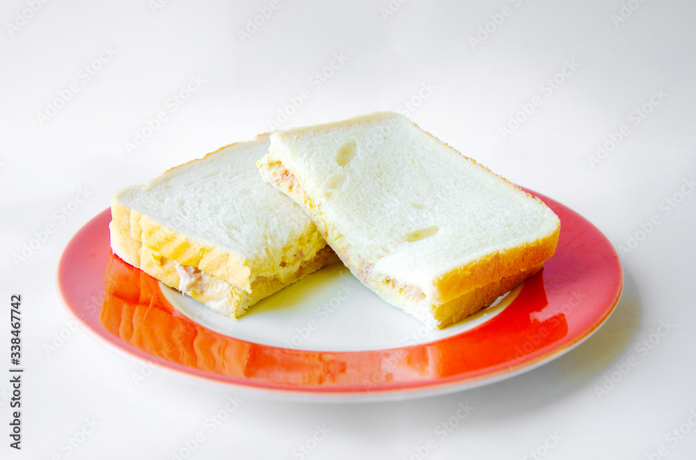 A homemade tuna and mayonnaise sandwich on a plate shot against a while background. 