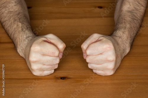 anger management, two hands fists on wooden table clench hairy man fists symbol angry