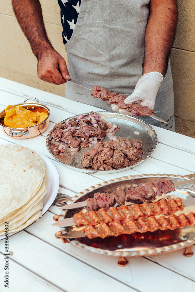Process of making kebab. Meat on skewer. Cooker follow hygiene and use gloves. Mixed grill. Traditional arabic dish. Family dinner. Real photos of cooking
