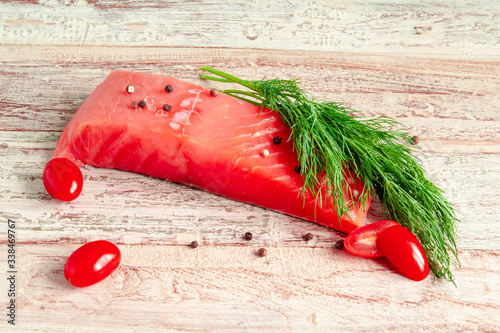 Sliced piece of salmon, cherry tomatoes and greens on the table photo