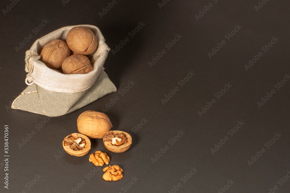 Walnuts scattered from a canvas bag on a black background. View from above. Place for text. Сopy space...