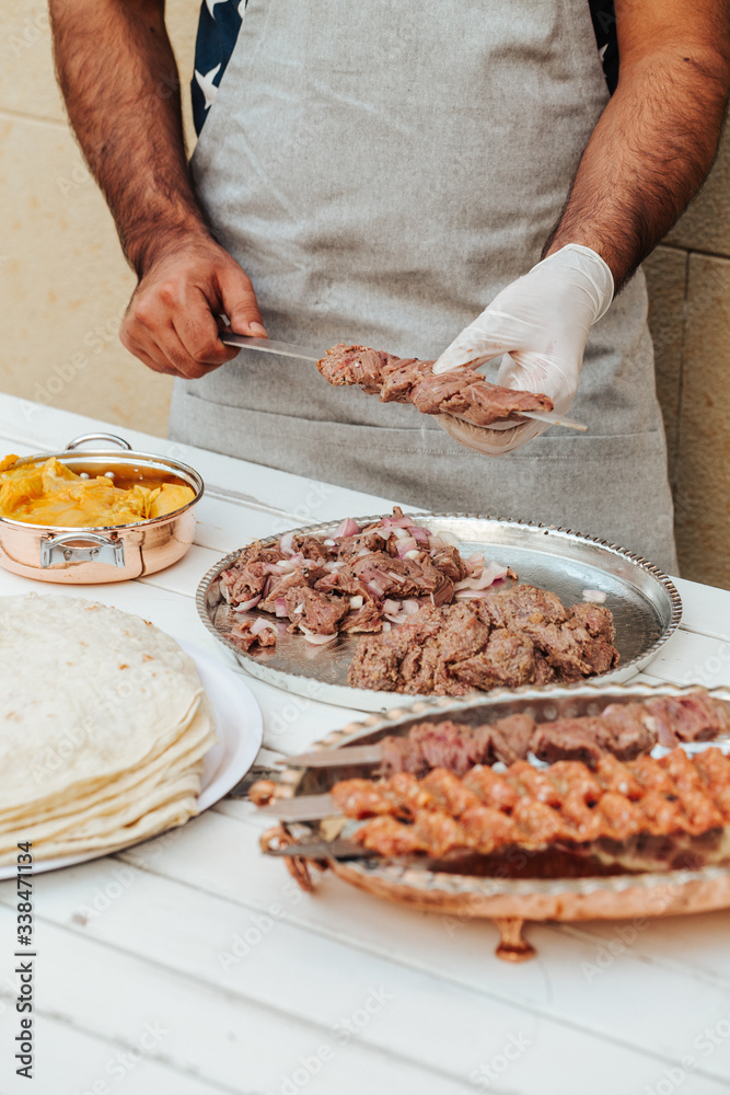 Process of making kebab. Meat on skewer. Cooker follow hygiene and use gloves. Mixed grill. Traditional arabic dish. Family dinner. Real photos of cooking