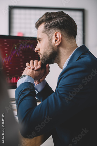 Selective focus of computer systems analyst looking at charts on computer monitor