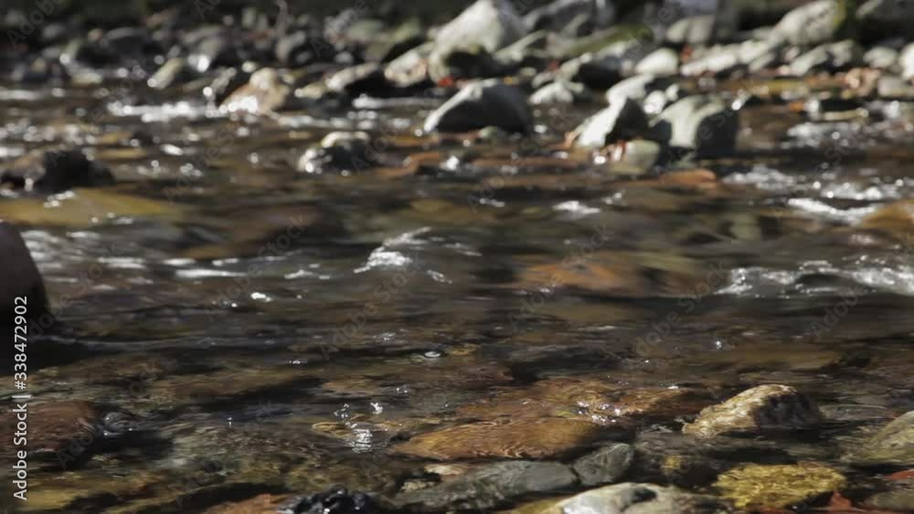Clear mountain stream moving over rocks, low angle slider upstream Clear mountain stream moving over rocks, low angle slider upstream