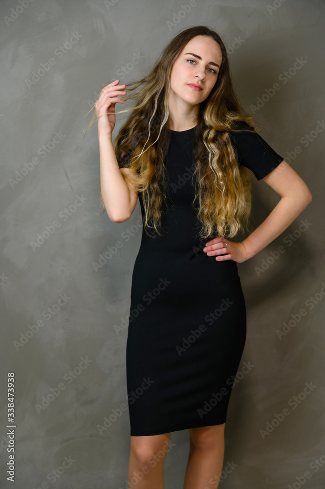 Vertical photo style girl with beautiful long hair in a black dress on a gray background in the studio Vertical photo style girl with beautiful long hair in a black dress on a gray background in the studio