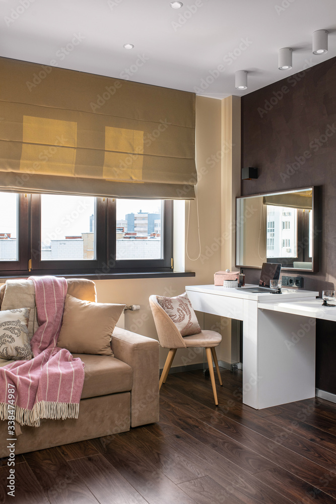 Fototapeta premium Interior photo. Space for work away. A cozy sofa and a workplace - a white table, a chair and a laptop. Telework