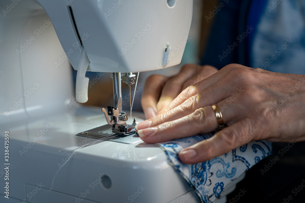 A seamstress sews material on a sewing machine.