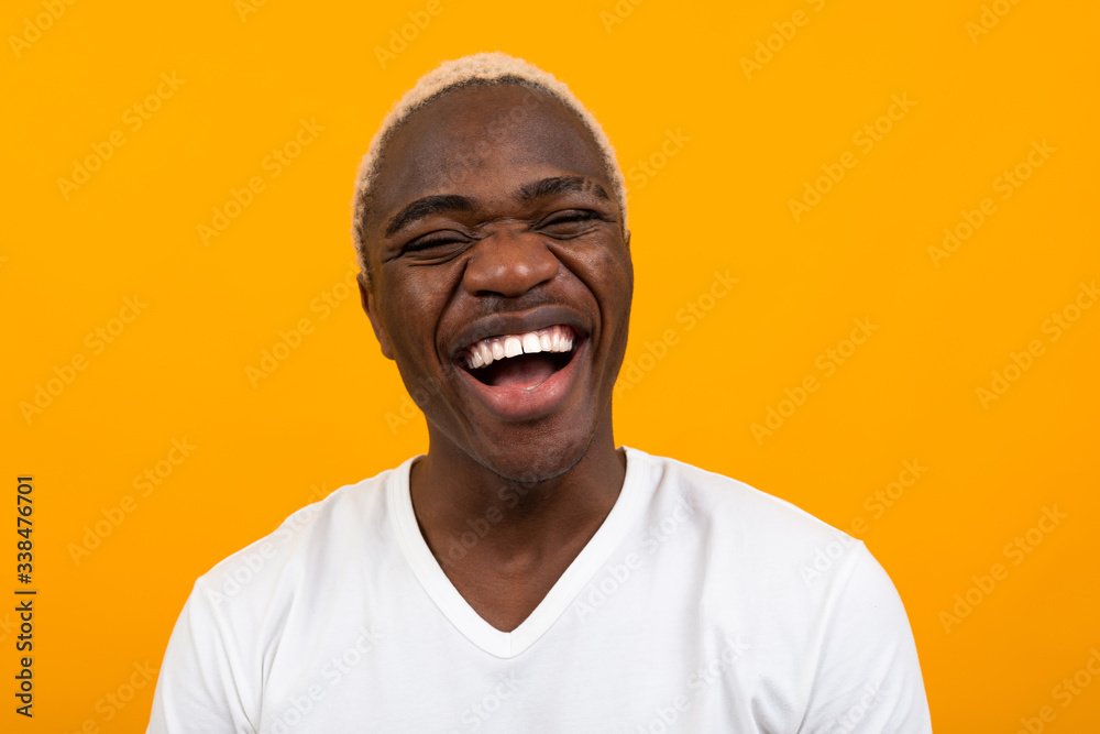 Closeup portrait of a smiling handsome black blond African man on an orange studio background Closeup portrait of a smiling handsome black blond African man on an orange studio background