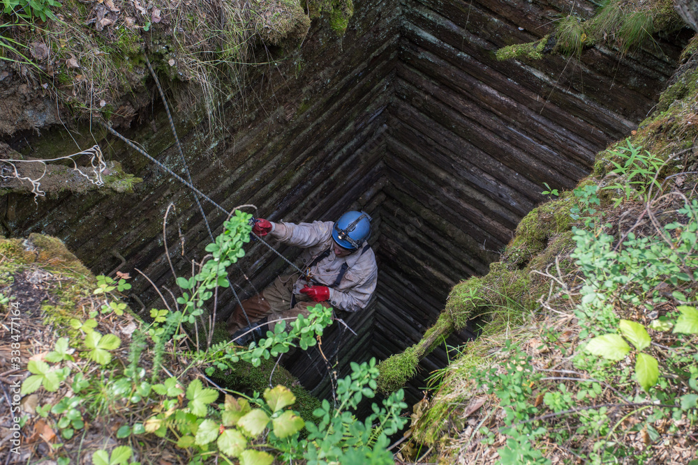 Old abandoned mine with wooden timbering and miner explorer climbing at rope Old abandoned mine with wooden timbering and miner explorer climbing at rope