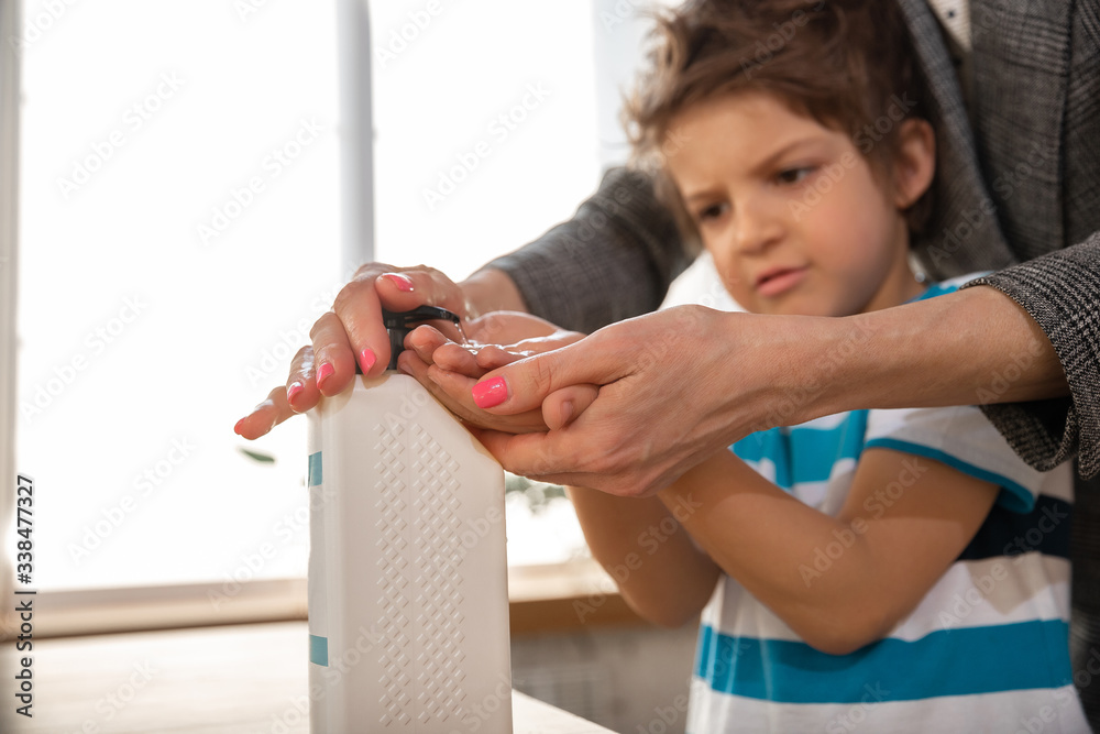 Obraz premium Mother washing hands her son carefully with soap and sanitizer, close up. Prevention of pneumonia virus spreading, protection against coronavirus pandemia. Hygiene, sanitary, cleanliness, disinfection