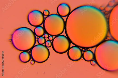 Orange colored oil bubbles in a liquid. Beautiful structure of oil and water in macro as abstract background.