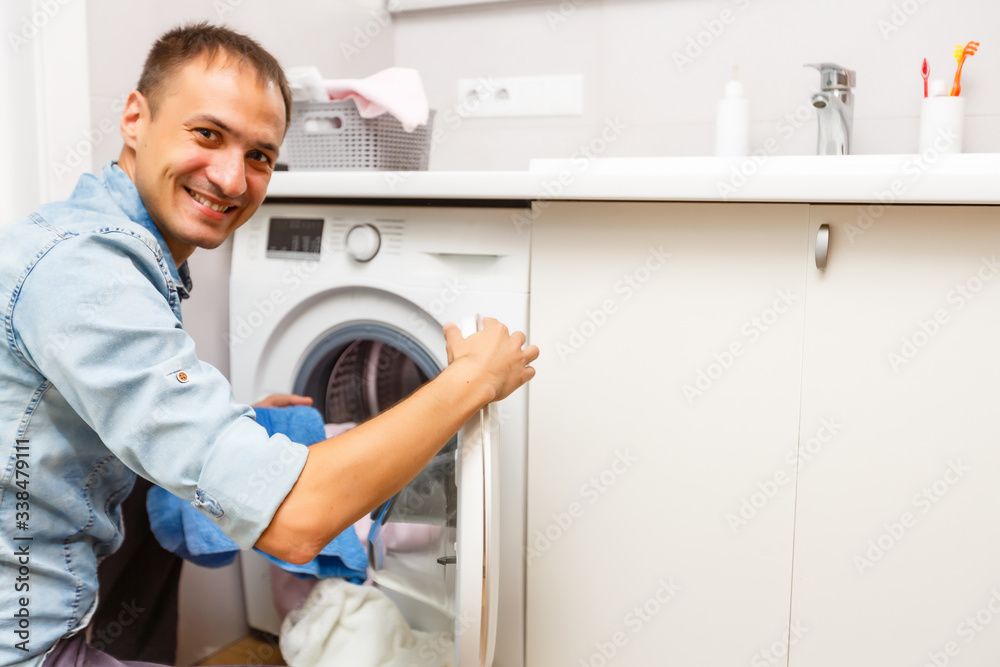 Man loading cloths to washing machine. View from inside the washing machine.