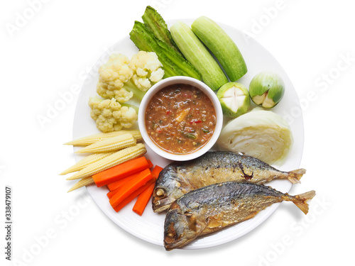 Top view of traditional thai food with chili shrimp paste or nam prik kapi, fried mackerel and boiled vegetables on white plate isolated on white background.