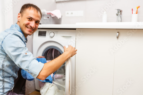 Man loading cloths to washing machine. View from inside the washing machine.