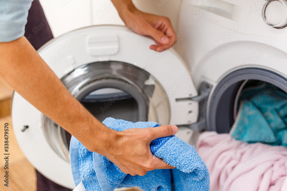 Man loading cloths to washing machine. View from inside the washing machine. Man loading cloths to washing machine. View from inside the washing machine.