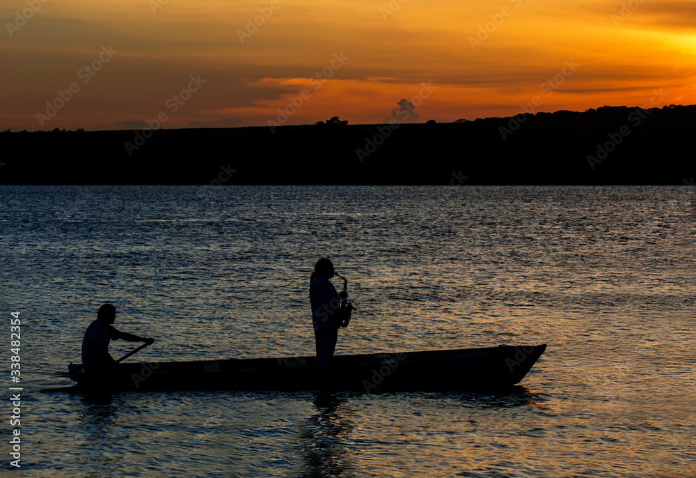 Sax played from inside a boat, during sunset . Jacaré River, Brazil.