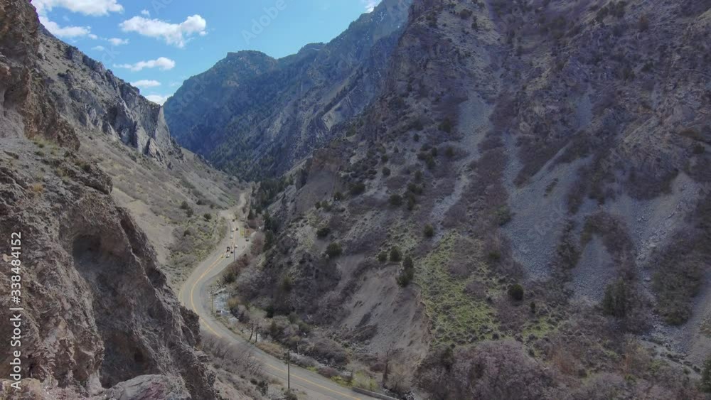 A high-altitude view of steep canyon slopes and a road at the bottom then fly backwards to hide the view behind jagged cliffs, rocky peak and brush breathtakingly close to the canyon cliff A high-altitude view of steep canyon slopes and a road at the bottom then fly backwards to hide the view behind jagged cliffs, rocky peak and brush breathtakingly close to the canyon cliff