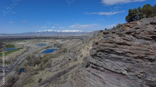 View of a large urban valley with suburbs and golf courses then flying backwards to reveal the location on top of a rugged mountain peak high above the city photo