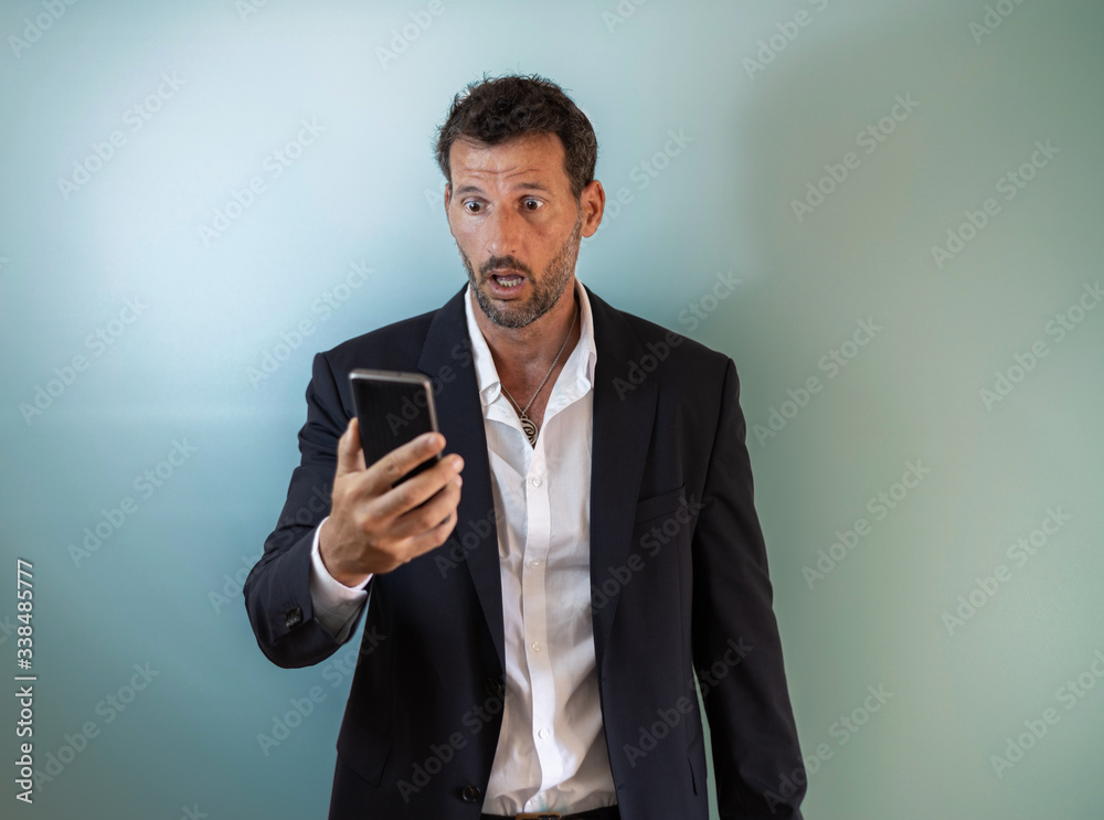 businessman with expression of surprise when reading a message on the phone businessman with expression of surprise when reading a message on the phone