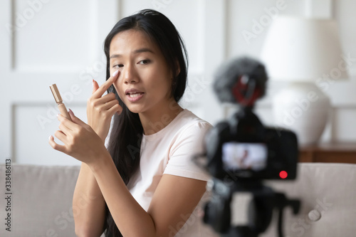 Make up artist records video on camcorder vlog teach how use concealer corrector apply foundation under eye area. Asian influencer advertise for audience internet viewers new cosmetics product concept