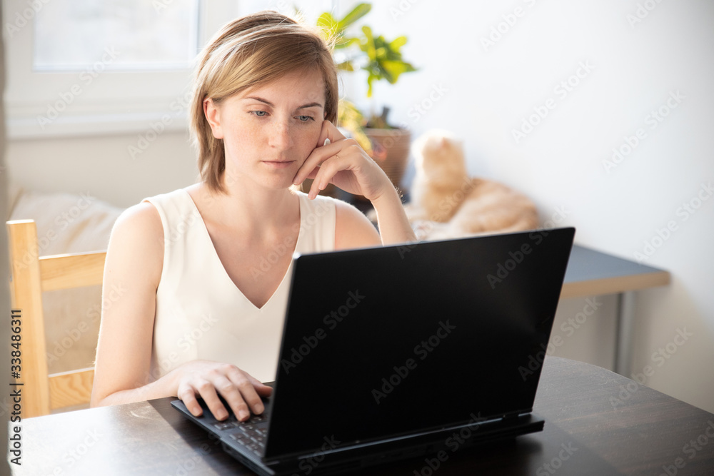 A woman in home clothes works on a computer in front of a monitor in a home atmosphere. Flexible working hours and remote work. Clouse-up A woman in home clothes works on a computer in front of a monitor in a home atmosphere. Flexible working hours and remote work. Clouse-up